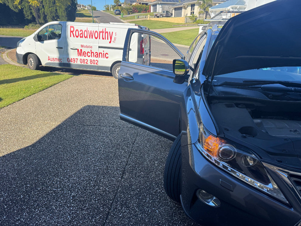 Our mechanic meticulously checking the engine bay during a pre purchase car inspection near Albany Creek to identify any potential mechanical issues. Blue car with open hood next to a van labeled 'Roadworthy Mechanic' on a residential street.