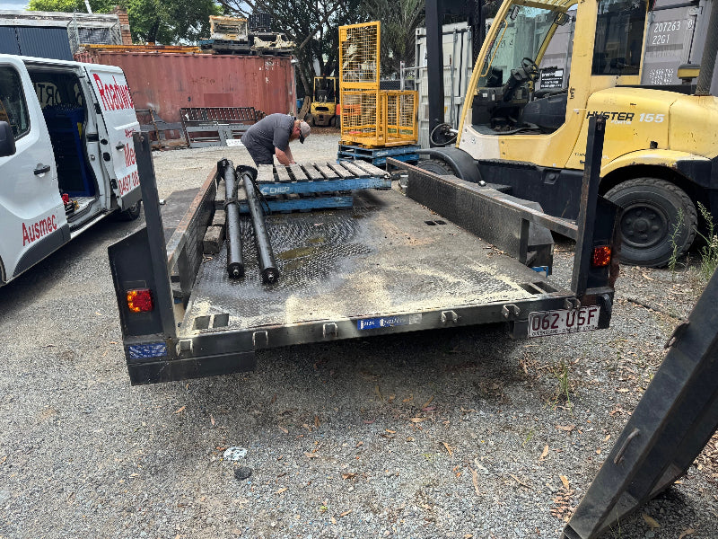 Car trailer good to go for RWC
Alt text: Car trailer ready for its Bald Hills Mobile Roadworthy (Safety Certificate) inspection, ensuring it's safe and compliant for the road. Trailer with a man loading materials, surrounded by vehicles and equipment.
