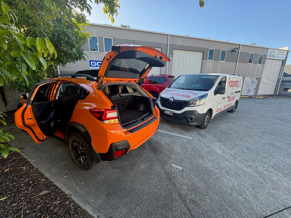 Orange SUV with open trunk in a parking lot with a white van in the background. An in-depth pre-purchase car inspection with all doors open, ensuring every part of the vehicle is checked near Chermside West