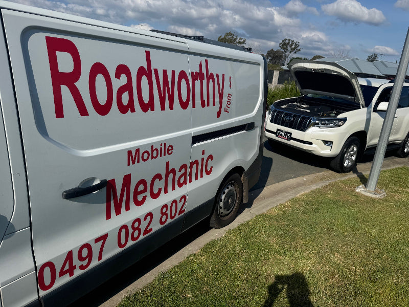 Roadworthy mobile mechanic van parked next to a white car with an open hood on a sunny day.