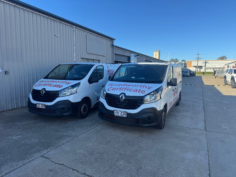Two Ausmec Mobile Roadworthy vehicles en route to provide prompt Everton Hills Safety Certificate inspections for your convenience. Two vans parked outside a building with 'Roadworthy Certificate' text on them.