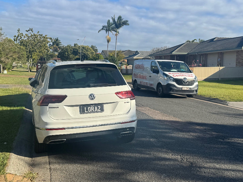 "Car prepared for its Redcliffe Mobile Roadworthy (Safety Certificate) at a customer's home, showcasing our convenient mobile RWC service." Two cars on a residential street with houses and palm trees in the background.