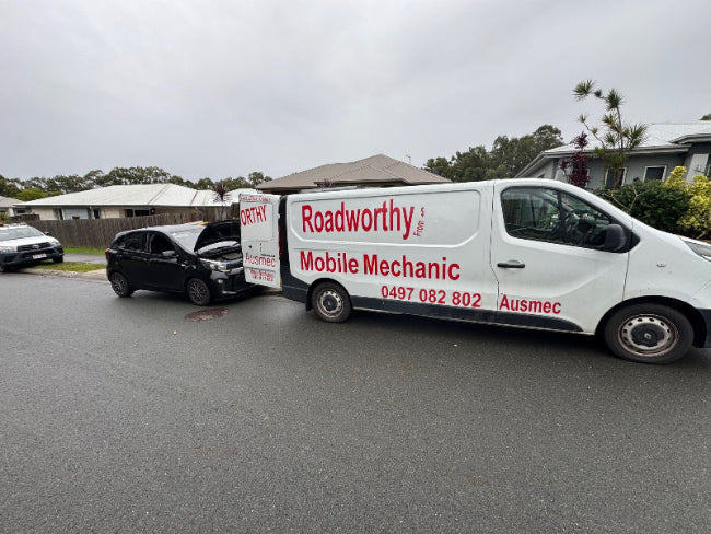 A black car undergoes a Clontarf mobile Roadworthy (Safety Certificate) inspection at the rear of one of our mobile inspection units.