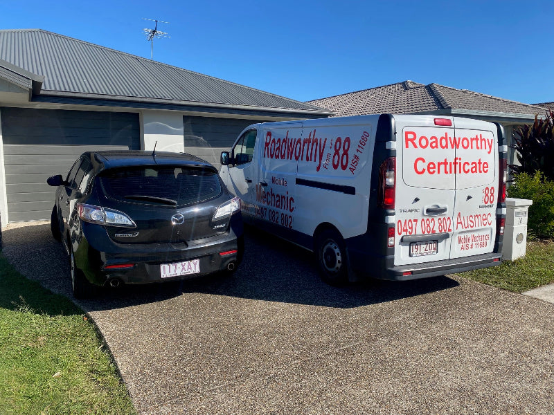 "Convenient Murrumba Downs Mobile Roadworthy (Safety Certificate) being conducted on a customer's car in their driveway by an Ausmec mechanic." Van with Roadworthy branding parked next to a car on a driveway.