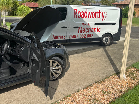 "Qualified mechanic performing a Burpengary Mobile Roadworthy (Safety Certificate) inspection on a car directly in a customer's driveway." Van from 'Roadworthy Mobile Mechanic' with a car's hood open on a driveway.