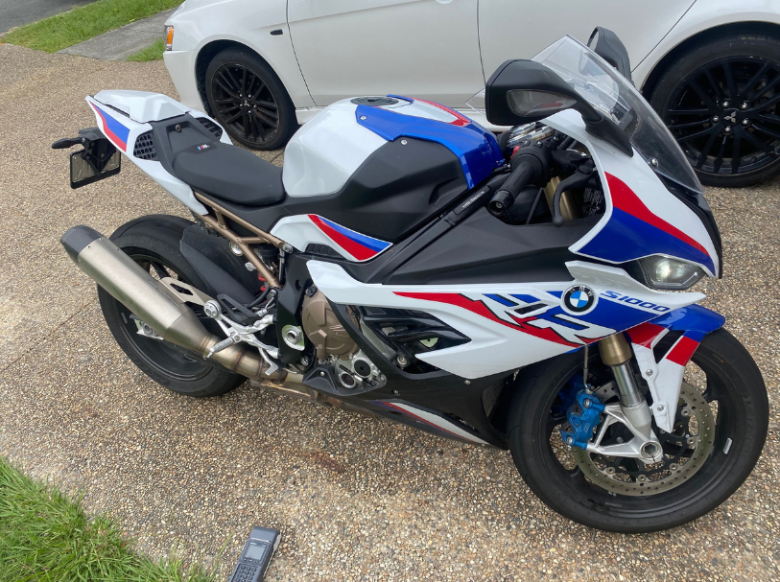 A motorcycle undergoing a thorough safety inspection in a residential driveway, receiving its Deagon Mobile Roadworthy (Safety Certificate) on-site.