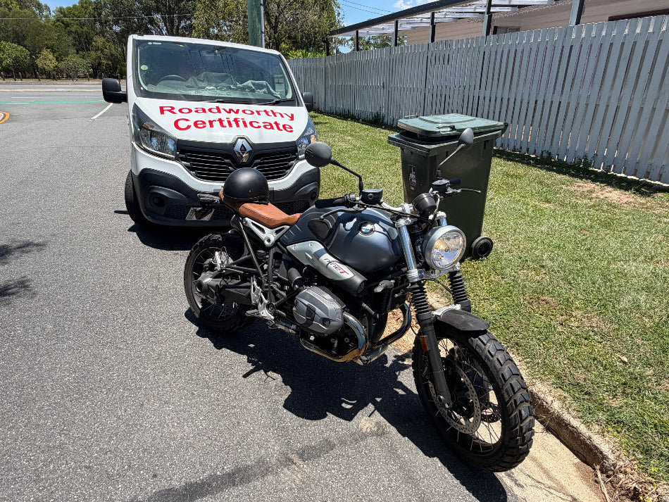 Motorcycle parked on a road with a van in the background displaying a 'Roadworthy Certificate' in Carseldine.