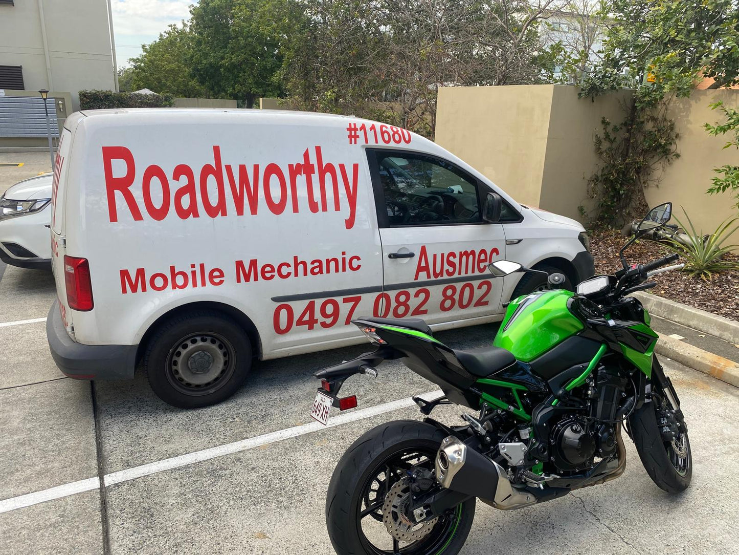 White van with 'Roadworthy' branding and a green motorcycle in a parking lot in Virginia