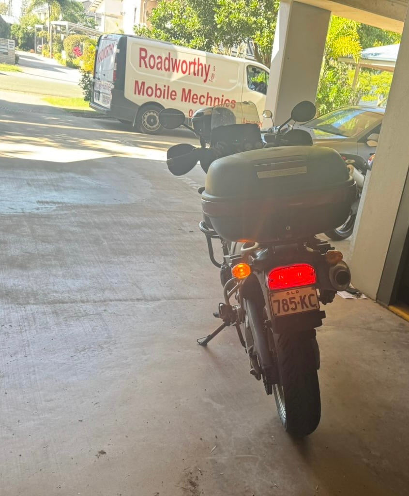 Motorcycle parked inside a garage with a van labeled 'Roadworthy Mobile Mechanics' outside in Caboolture South