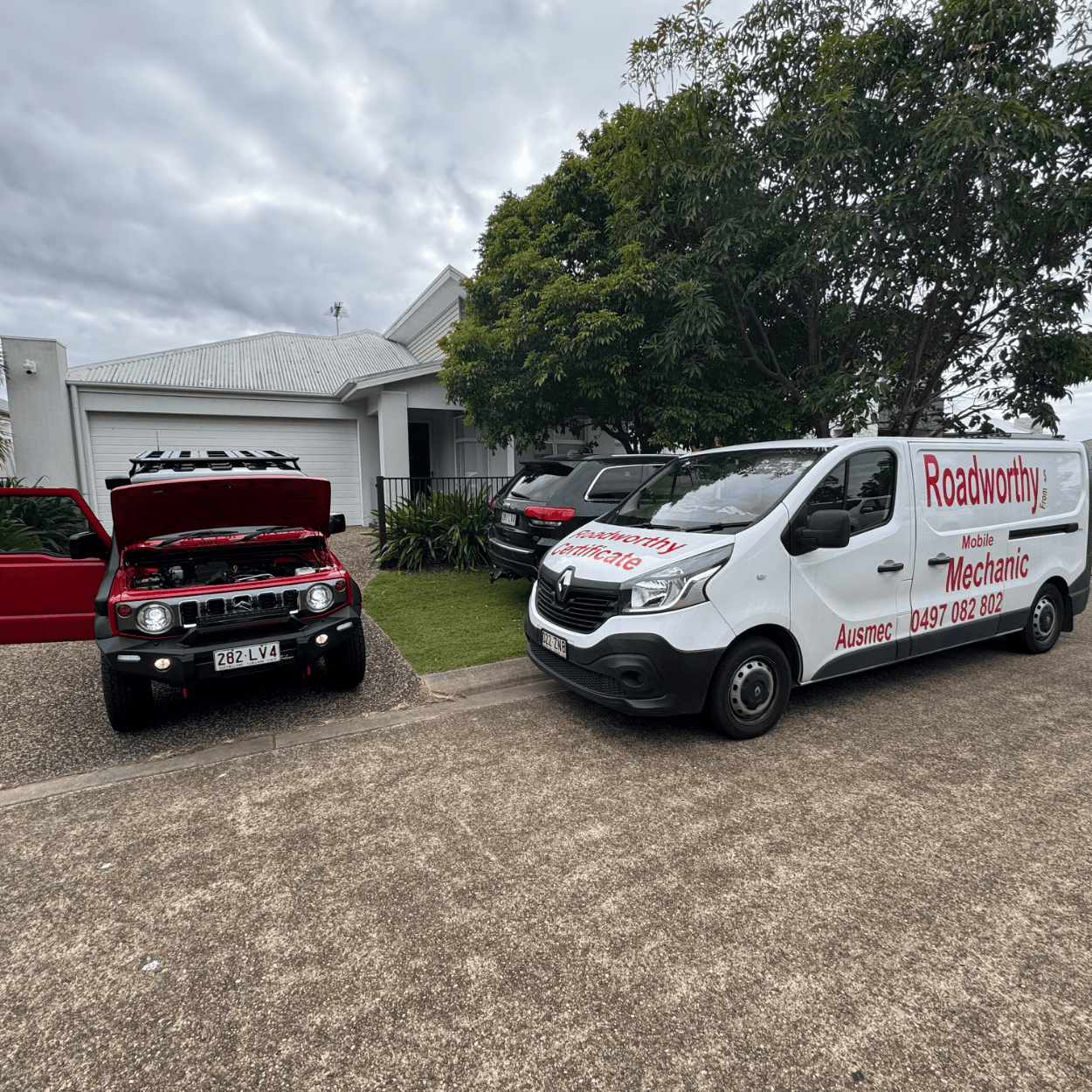"Red Suzuki Jimny undergoing a Morayfield Mobile Roadworthy (Safety certificate) inspection conveniently at a customer's driveway." Two vehicles, one red and one white with branding, parked on a driveway.