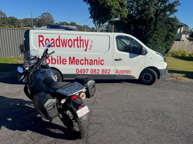 "Thorough motorcycle check underway for a Sandgate Mobile Roadworthy (Safety Certificate), ensuring bike compliance." White van with 'Readworthy Mobile Mechanic' branding next to a motorcycle on a road.