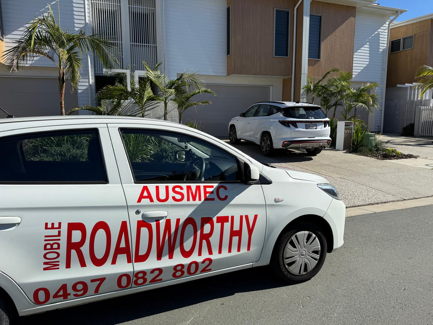 "Our AIS-approved mobile unit brings Taigum Mobile Roadworthy (Safety Certificate) inspections to you." Car with 'AUSMEC MOBILE ROADWORTHY' branding on a residential street.