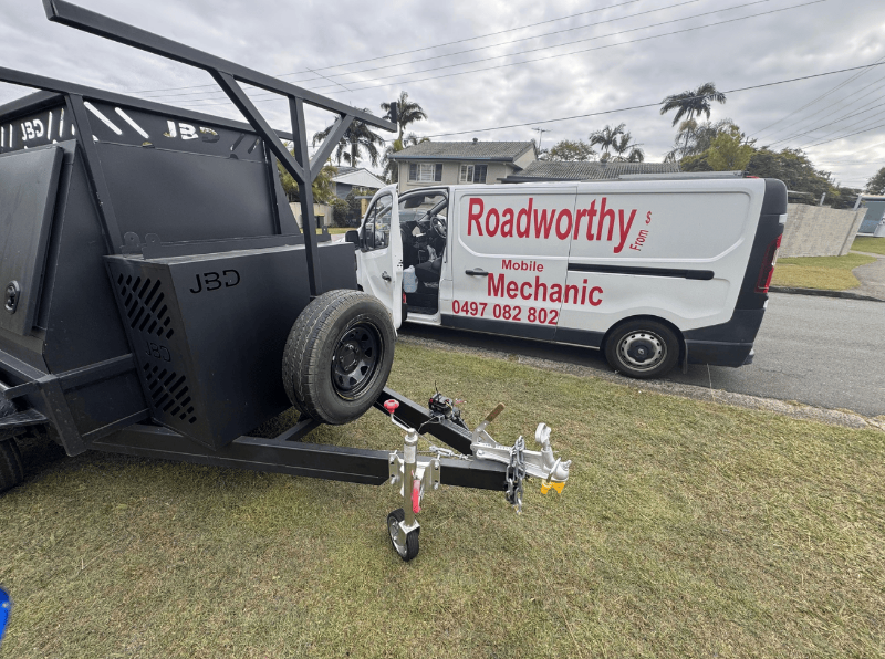 "Box trailer undergoing a thorough Caboolture South Mobile Roadworthy (Safety certificate) inspection by Ausmec mobile team."JBD trailer attached to a Roadworthy Mobile Mechanic van on a grassy area.