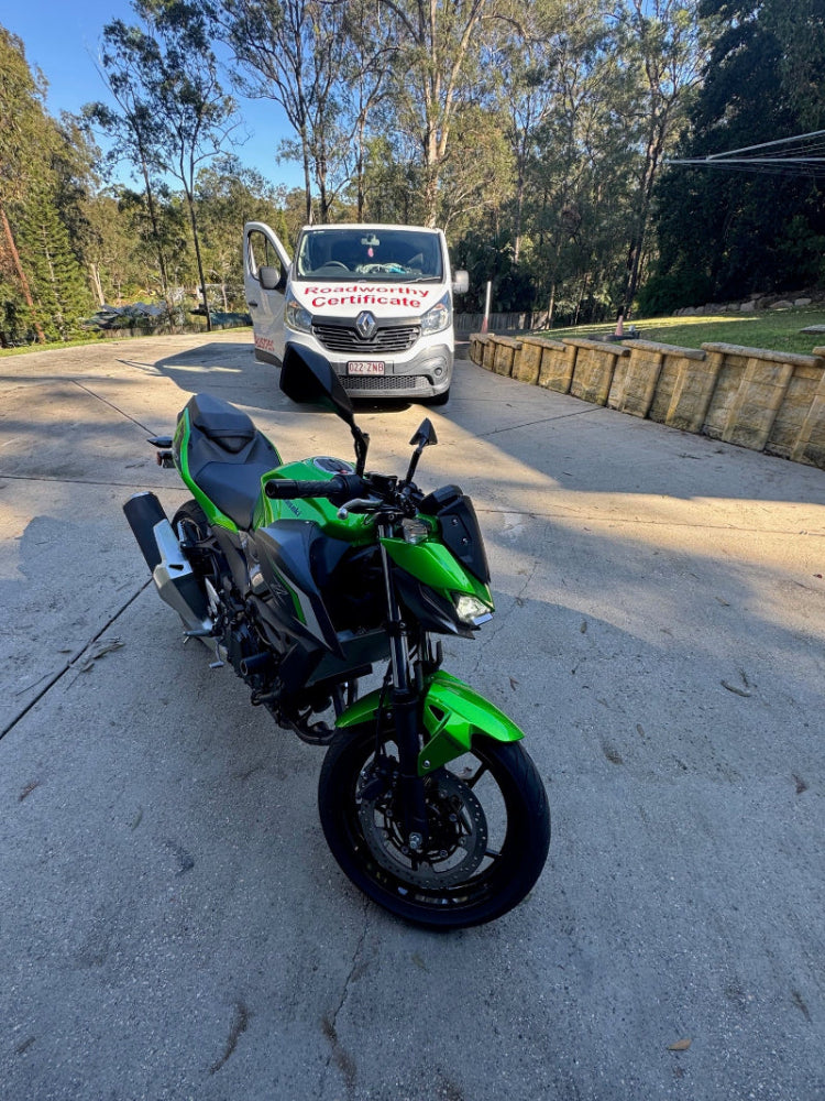 Motorcycle inspection in road
Alt text: Thorough mobile roadworthy inspection of a motorcycle on location for a Wavell Heights customer seeking a safety certificate. Green motorcycle parked on a road with trees and a building in the background