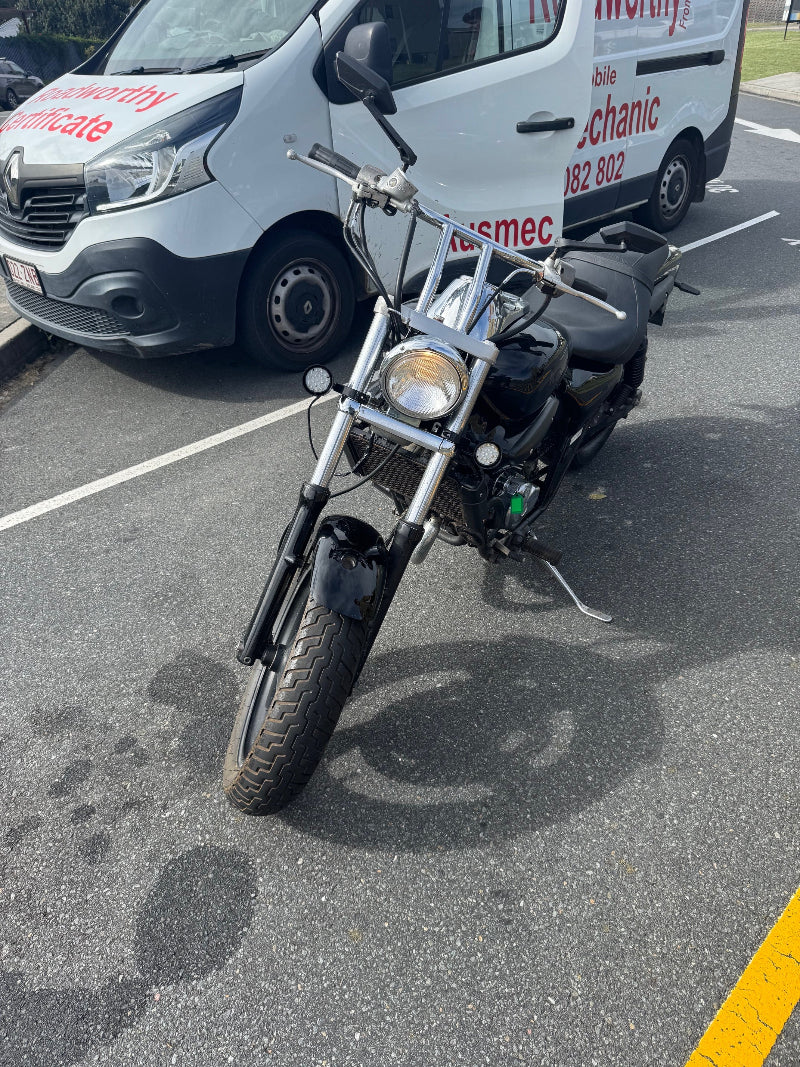 Zillmere Mobile Roadworthy (Safety Certificate) for motorcycles and mopeds – Getting your two-wheeler legally on the road is easy with our mobile service.Motorcycle parked on a road with a white van in the background