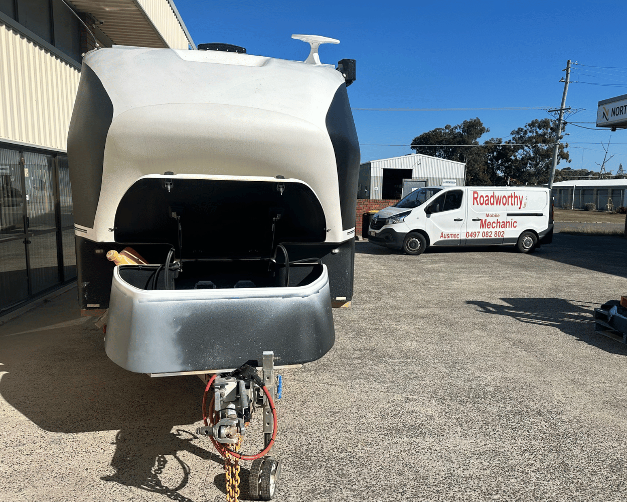 "Qualified inspectors meticulously examining a horse float for a Murrumba Downs Mobile Roadworthy (Safety Certificate) in a car park." Back of a horse float with a van in the background