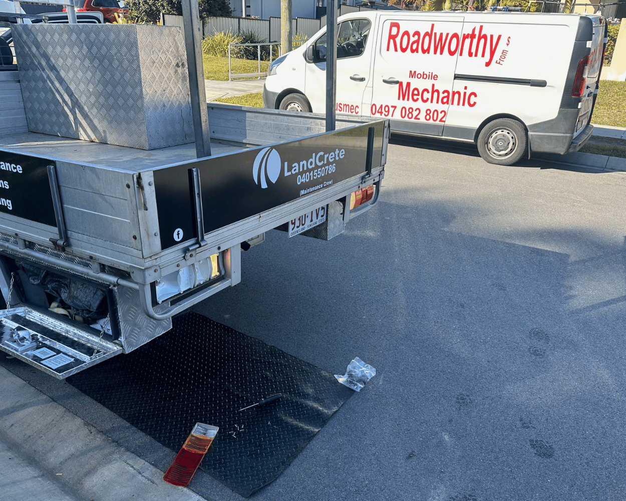 "Ute defects being repaired at a customer's home as part of the comprehensive Morayfield Mobile Roadworthy (Safety certificate) service."
Rear of a Ute with 'LandCrate' branding and a white van with 'Roadworthy' branding in the background.