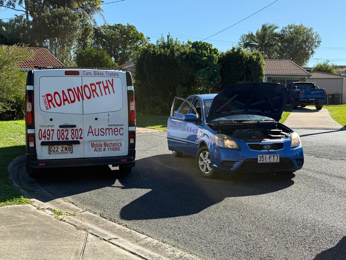 Our inspector performing a meticulous pre purchase car inspection Near Albion with the bonnet and doors open, checking all crucial components. Van with 'Roadworthy' branding next to a blue car with its hood open on a residential street.