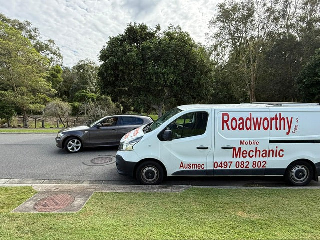 An Ausmec Mobile Roadworthy inspector conducting a thorough test drive of a car as part of an Ascot Mobile Roadworthy (Safety Certificate) inspection. White van with 'Roadworthy Mobile Mechanic' branding parked on a road with trees in the background.