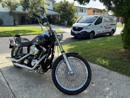 Black motorcycle parked on a driveway in Aspley with a Roadworthy Inspection vehicle in the background.
