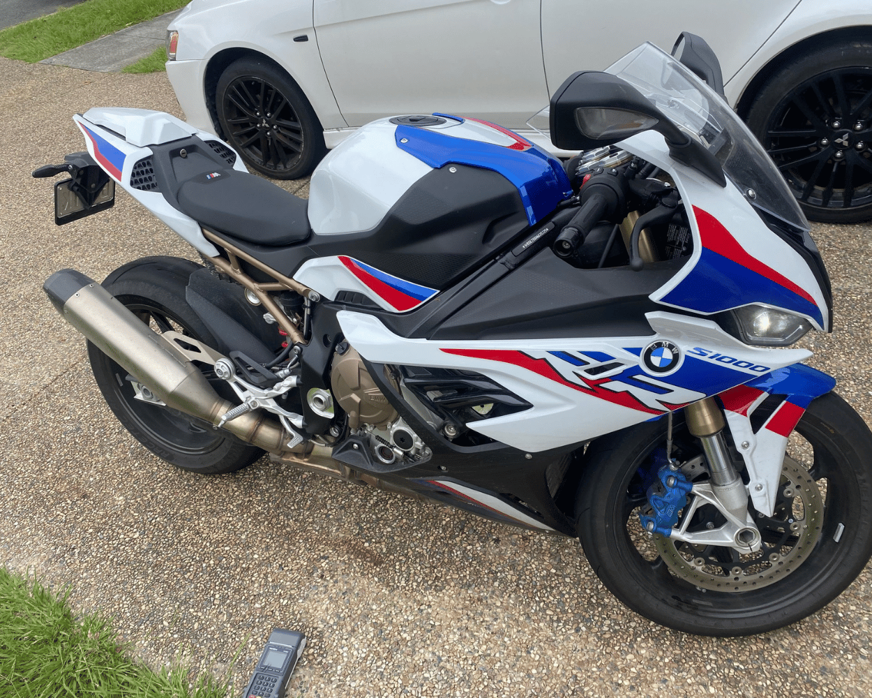 "BMW superbike receiving a meticulous Bellmere Mobile Roadworthy (Safety Certificate) inspection for transfer to its new owner."
 BMW motorcycle with red, white, and blue design parked on a driveway.