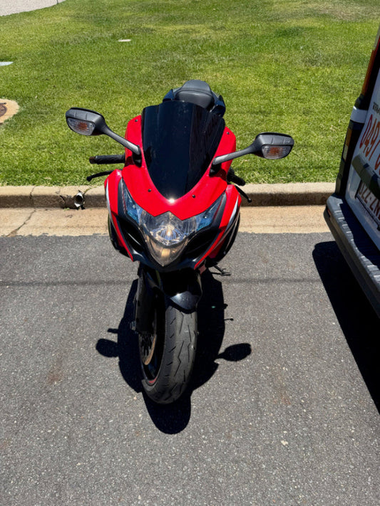 Red motorcycle parked on a driveway next to a grassy area in Bray Park