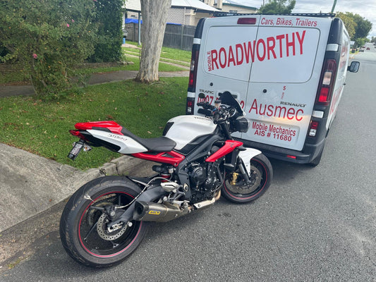 Motorcycle parked on a street next to a van with 'Roadworthy' branding in Burpengary East.
