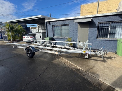 (Boat trailer inspection to register): "Thorough boat trailer inspection by Ausmec Mobile Roadworthy to assist with registration, ensuring it passes the Carseldine Mobile Roadworthy (Safety Certificate) requirements." White boat trailer parked on a driveway next to a building