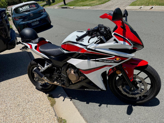 Red and white Honda motorcycle parked on a street in Cashmere for a Motorcycle Roadworthy Inspection.