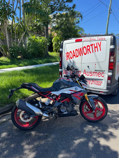 Motorcycle parked on a street with a van labeled 'Roadworthy' in the background in Eagle Farm