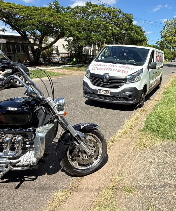 Motorcycle parked on the side of a road with a Roadworthy Certificate Inspection Van in the background in Eatons Hill