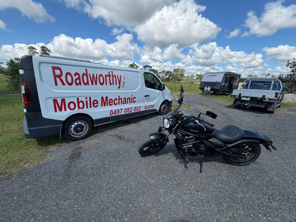 Roadworthy Mobile Mechanic van with a motorcycle on a road under a blue sky with clouds in Kelvin Grove