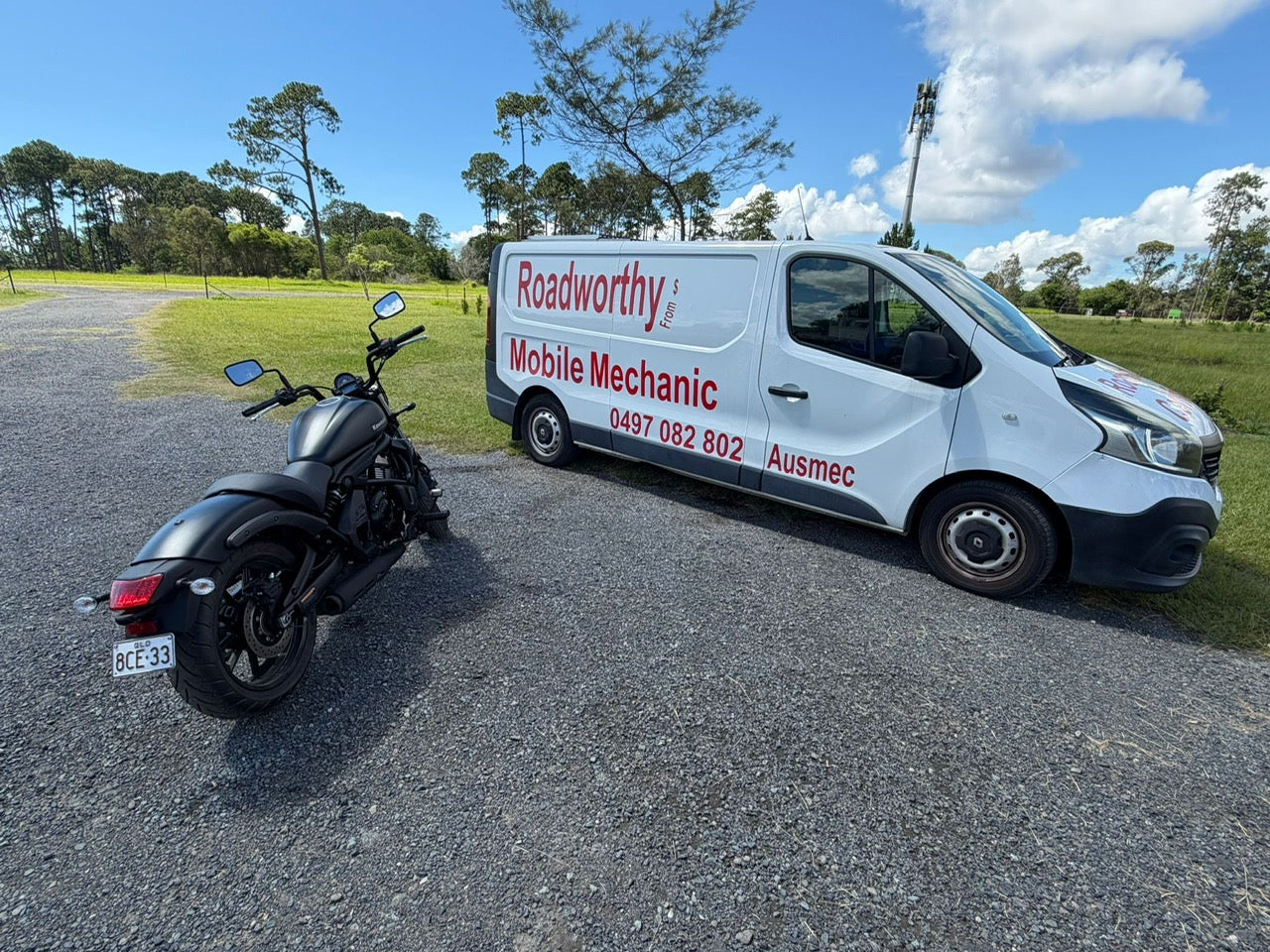 White van with 'Roadworthy' branding next to a black motorcycle on a road in Kippa-Ring