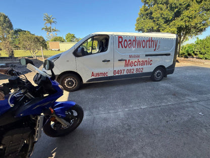 White van with 'Roadworthy' branding parked next to a blue motorcycle on a concrete surface in Lawnton