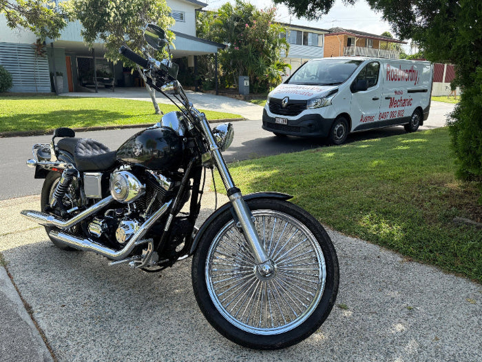 Black motorcycle parked on a driveway with a van in the background in McDowall