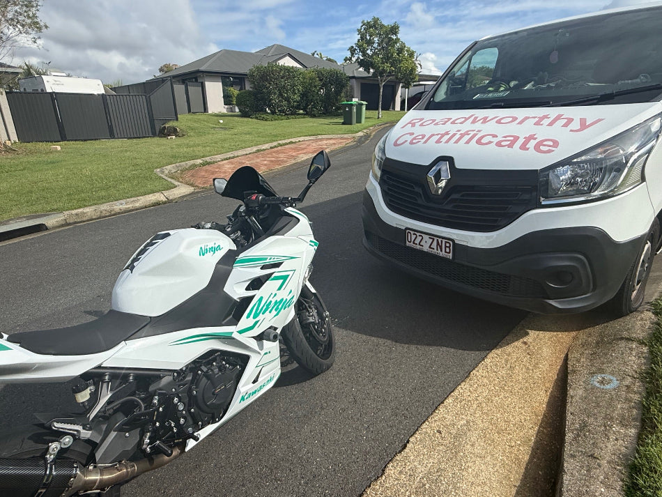 Motorcycle and van on a residential street with 'roadworthy certificate' text in Mitchelton.