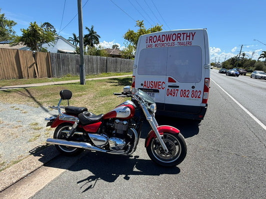 Motorcycle parked on the side of a road with a van labeled 'Roadworthy' in the background in Morayfield.