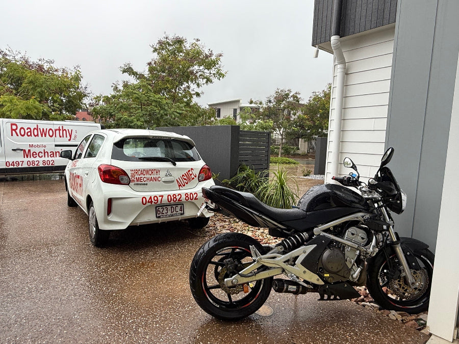Motorcycle parked on a wet driveway with a white Roadworthy Inspecton vehicle and building in the background in Everton Park.
