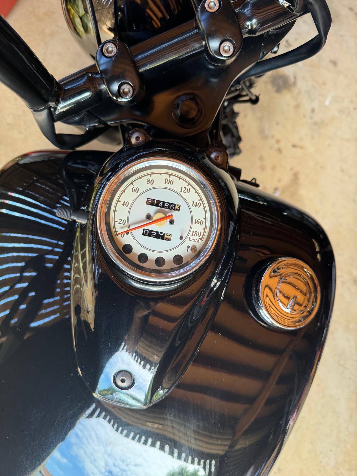 Close-up of a motorcycle gauge and emblem on a black fuel tank during a Roadworthy Inspection in Griffin