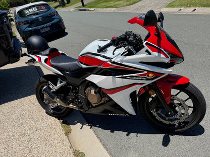 Red and white Honda motorcycle parked on a street for a motorcycle roadworthy inspection in Hendra