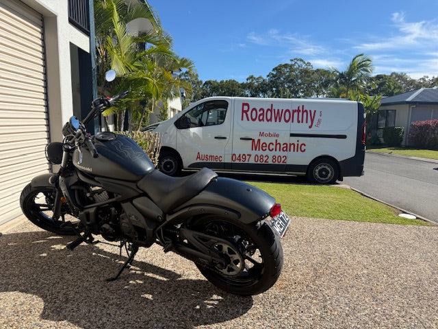 Black motorcycle parked on a driveway with a white van labeled 'Roadworthy Mobile Mechanic' in the background in Taigum