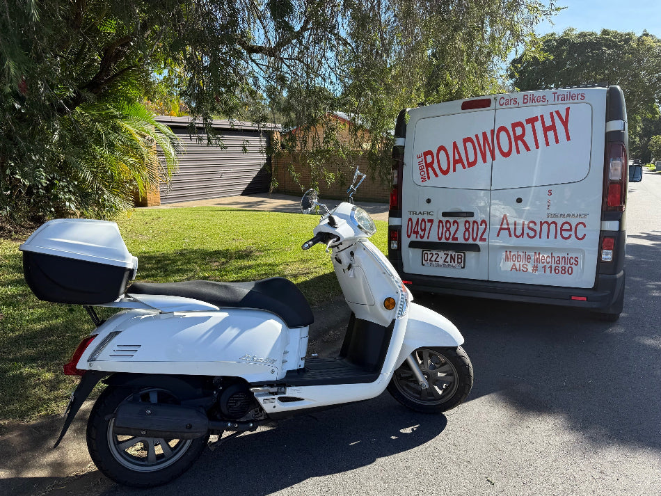 White scooter parked on a driveway with a van labeled 'The Roadworthy' in the background in Margate.