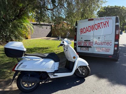 White scooter parked on a driveway with a van labeled 'The Roadworthy' in the background in Margate.