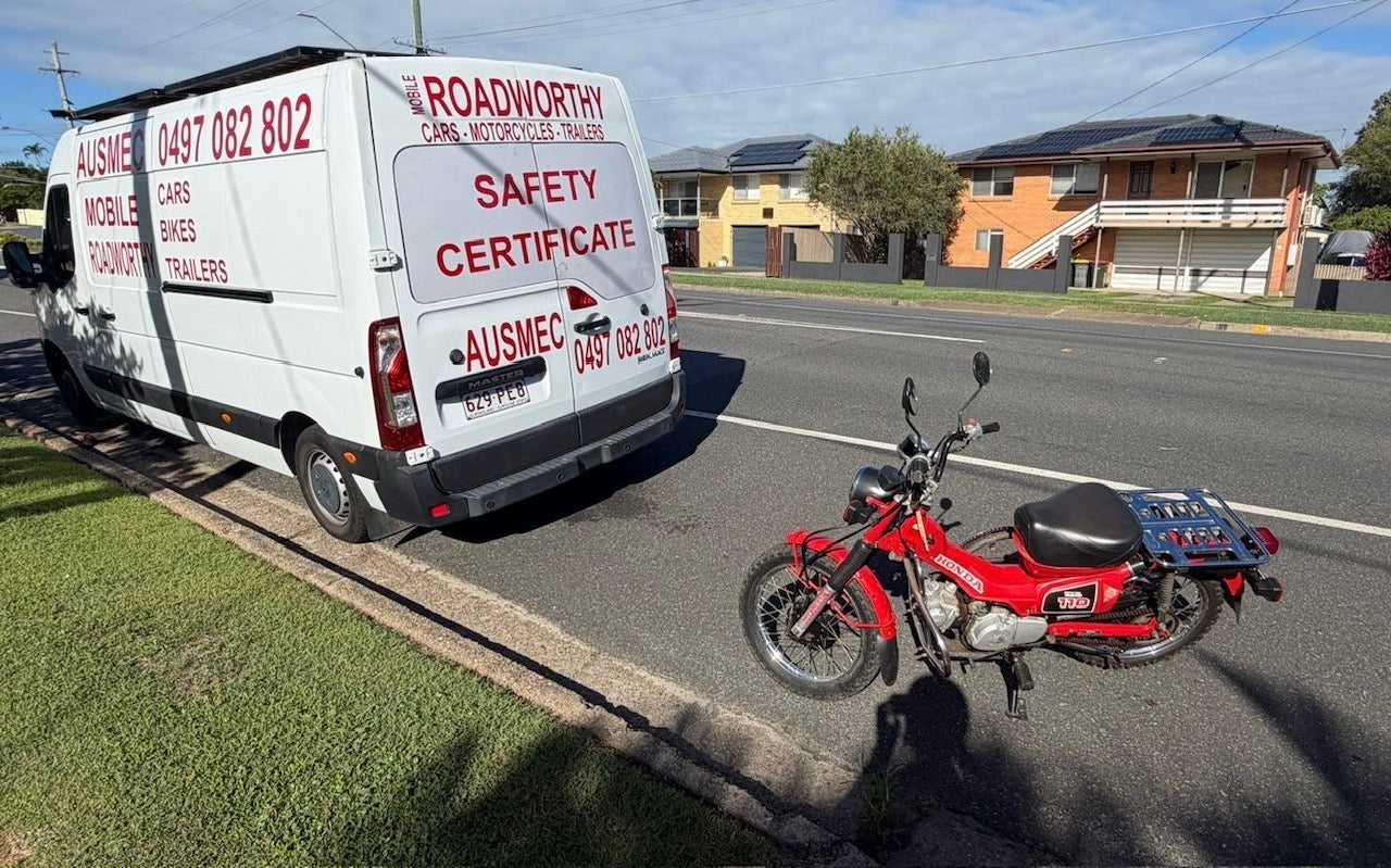 White van with 'Roadworthy Safety Certificate' sign on a residential street with a red motorcycle in Taigum
