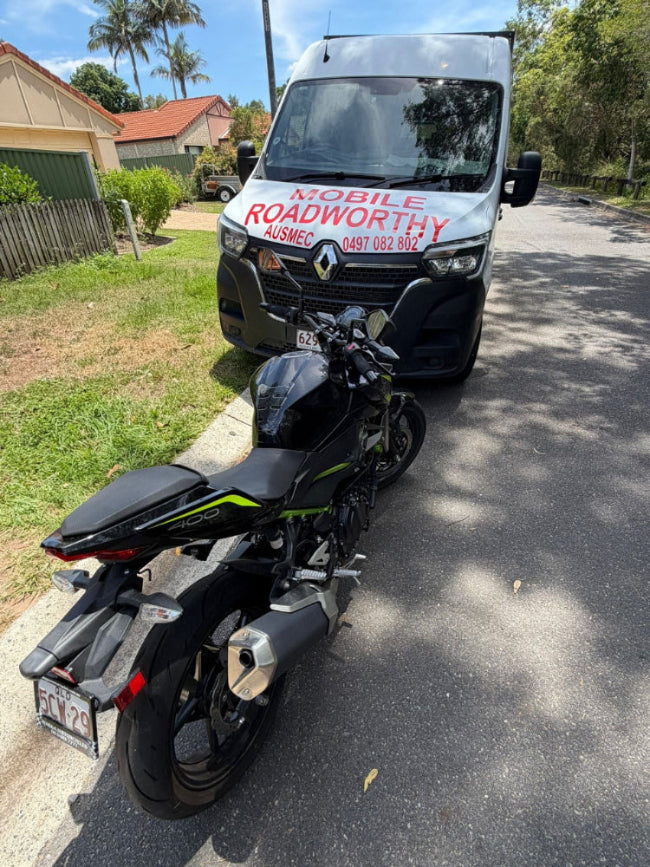 Motorcycle parked on a residential street with a van in the background displaying 'Mobile Roadworthy Ausmec' in North Lakes