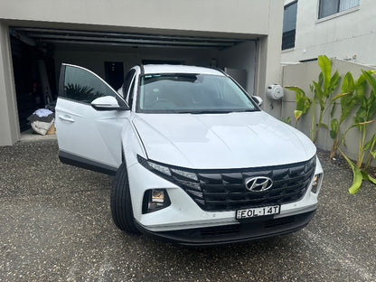 White car receiving inspection in driveway: A white car conveniently receives a safety inspection right in its driveway, highlighting the ease of obtaining a Brighton Mobile Roadworthy (Safety Certificate).