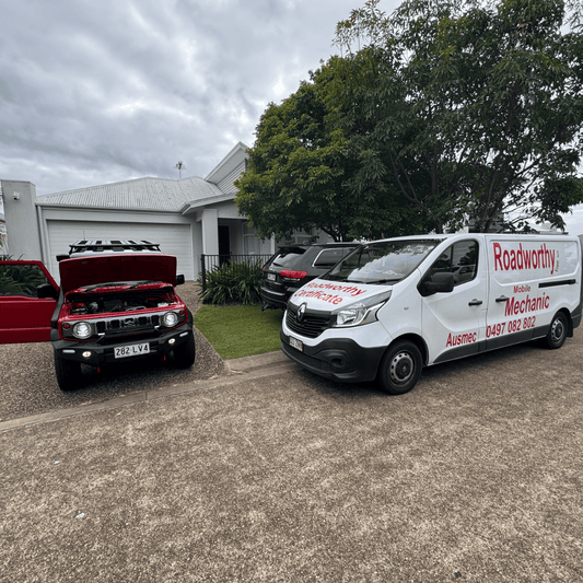  "Red Suzuki Jimny undergoing a Morayfield Mobile Roadworthy (Safety certificate) inspection conveniently at a customer's driveway." Two vehicles, one red and one white with branding, parked on a driveway.