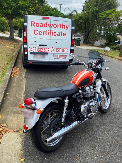Motorcycle parked on a street with a van labeled 'Roadworthy Certificate' in the background in Stafford
