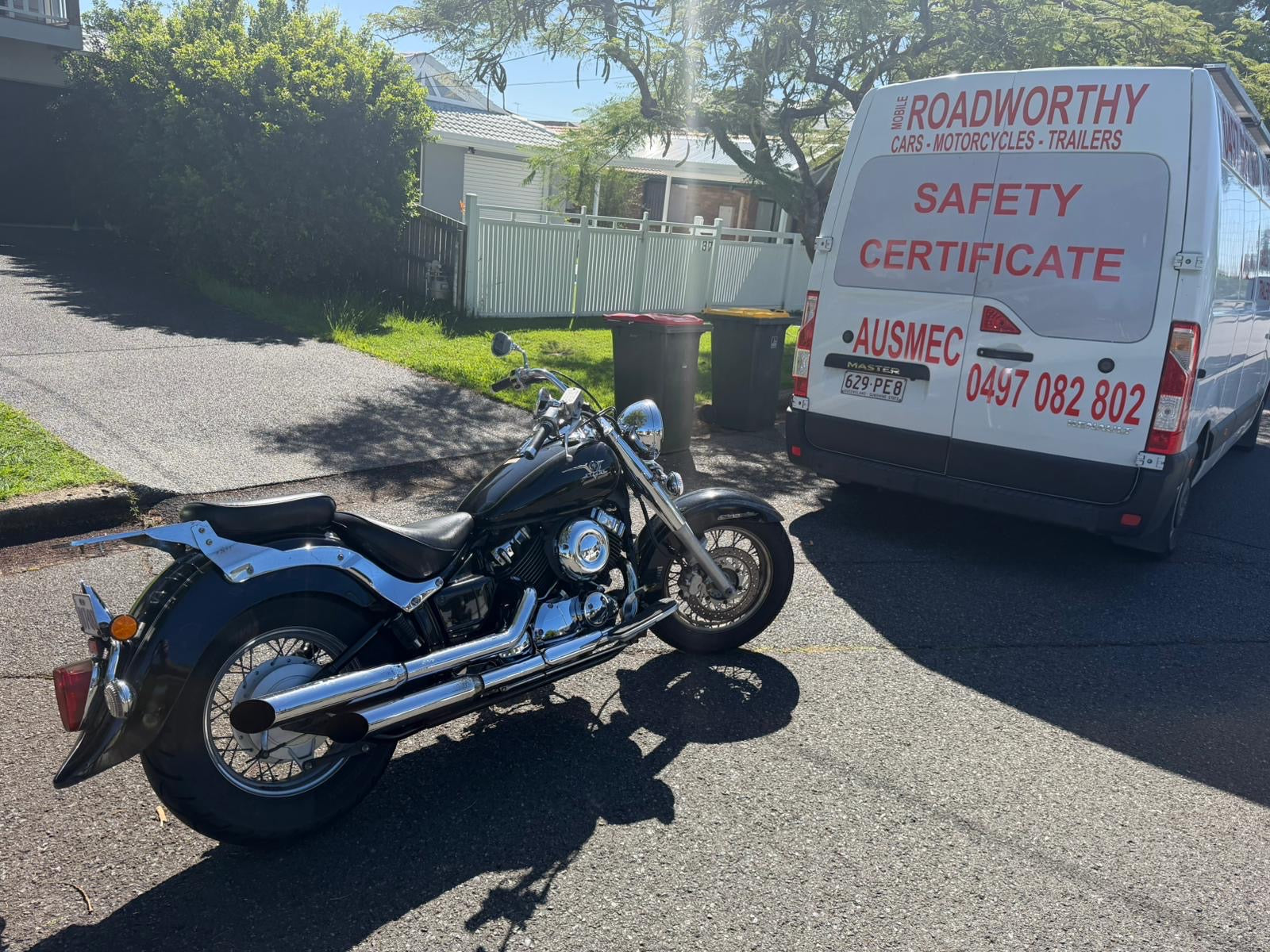 Motorcycle parked on a driveway with a van labeled 'Roadworthy Cars Motorcycles Trailers' in the background in Upper Caboolture