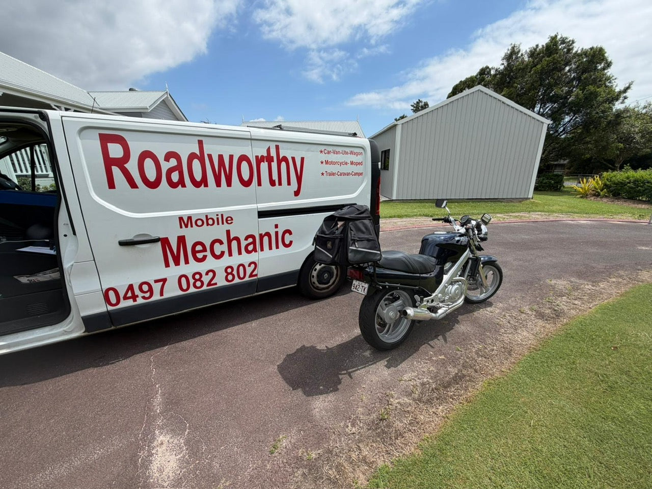 White van with 'Roadworthy' branding and a motorcycle on a driveway in Warner